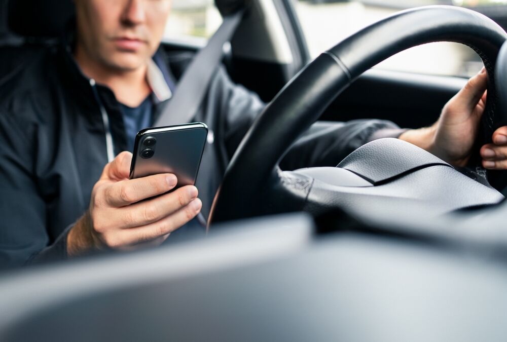 Driving distracted by phone. Car driver texting. Accident and crash danger. Man using mobile cellphone while on road. Irresponsible guy using text sms. No safety. Rideshare app in smartphone.
