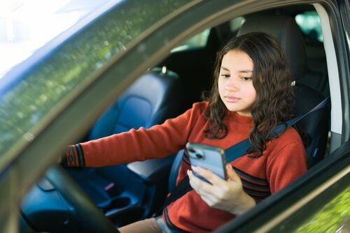 Abogado de accidentes automovilísticos en Seattle abordando riesgos de distracción al volante con conductora adolescente usando el celular.